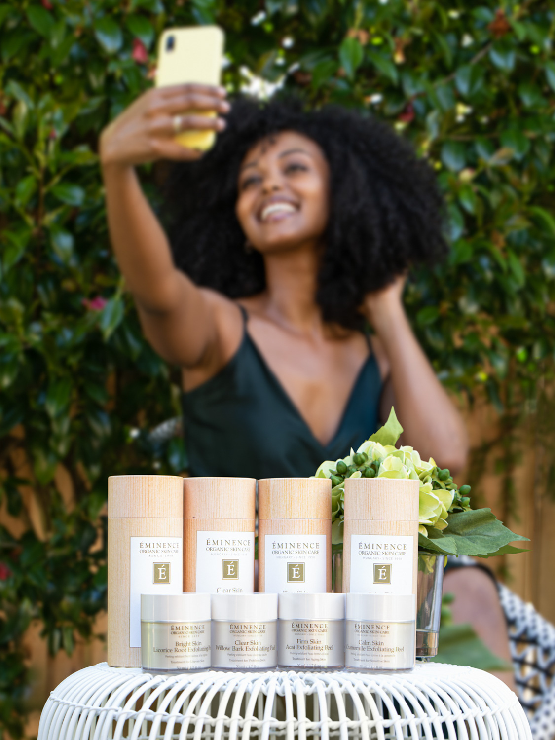 A woman posing with the Eminence Organics VitaSkin Peels including the Eminence Organics Firm Skin Acai Exfoliating Peel
