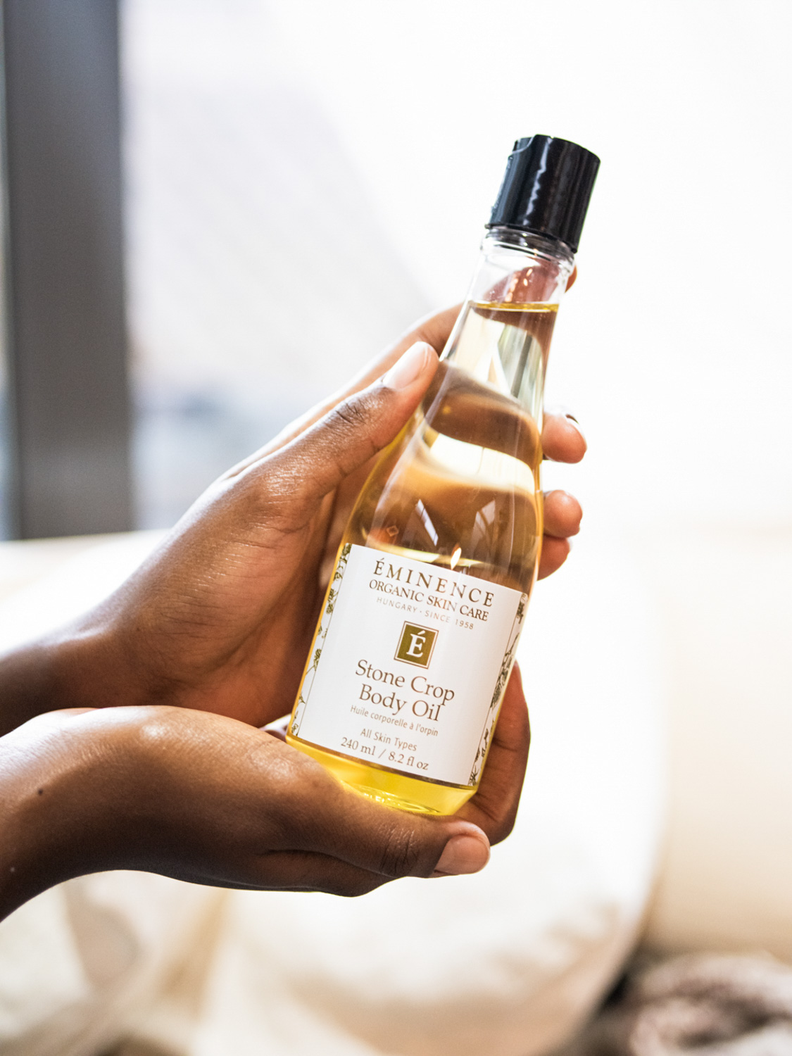 Hands holding the Eminence Organics Stone Crop Body Oil