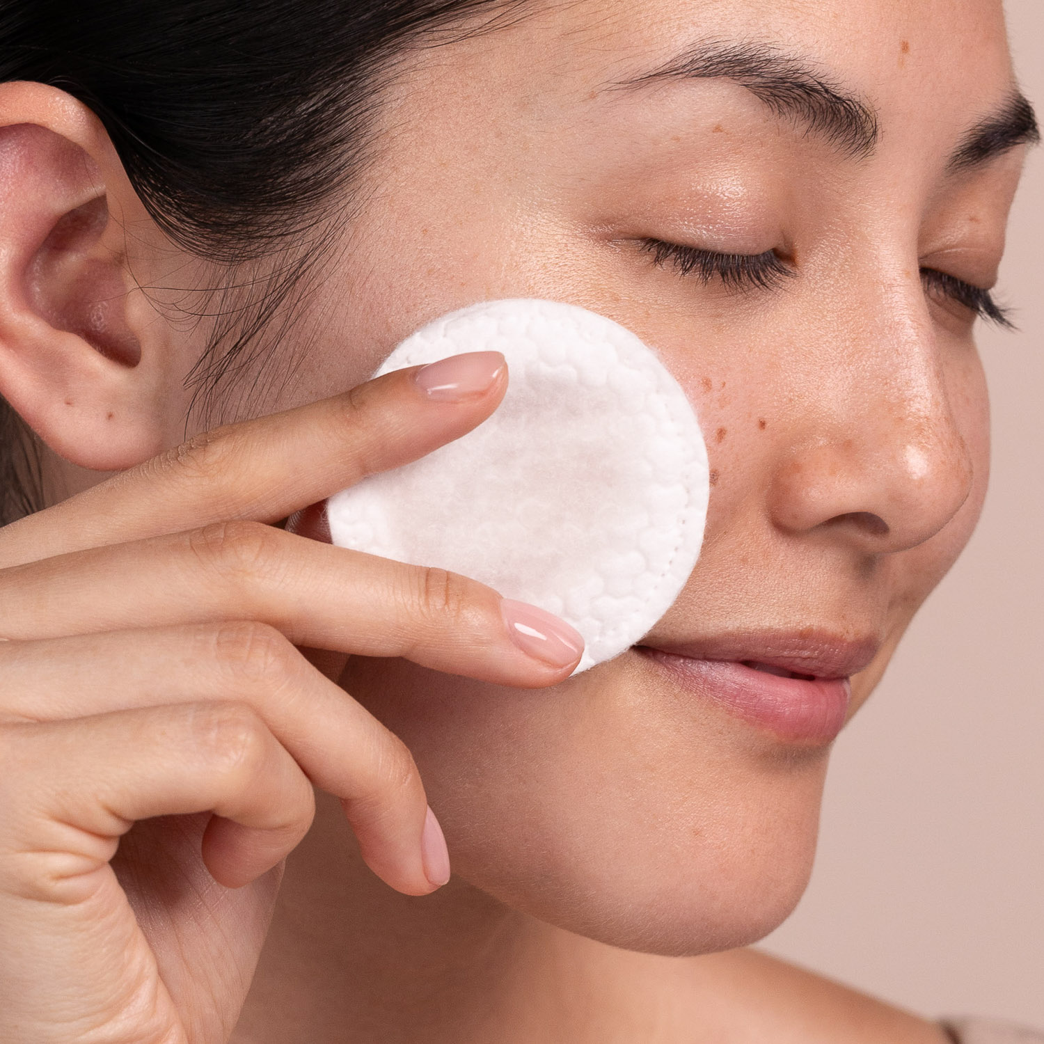 A woman applying Eminence Organics Bright Skin Licorice Root Exfoliating Peel to face