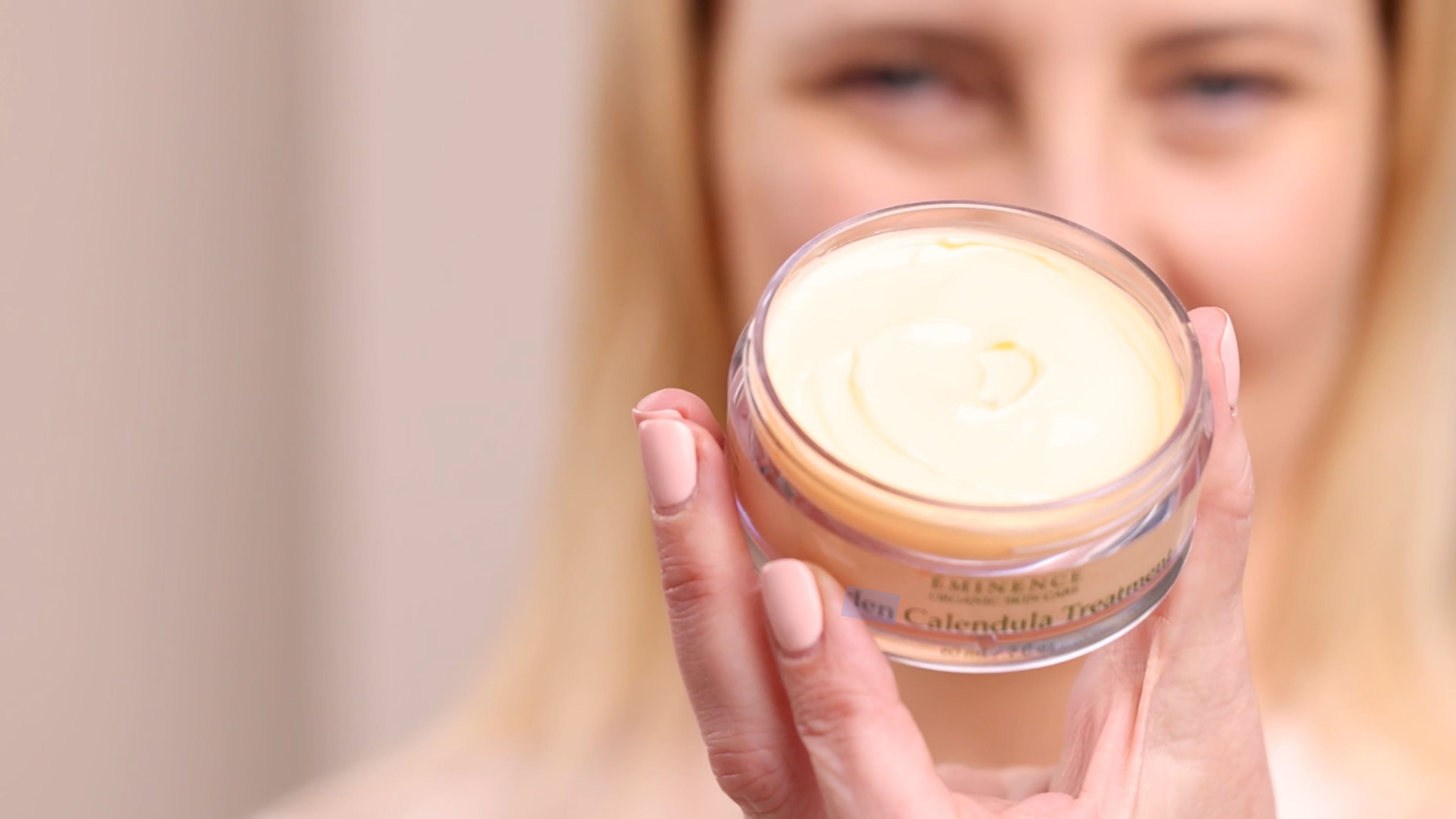 A woman holding the Eminence Organics Linden Calendula Treatment Jar