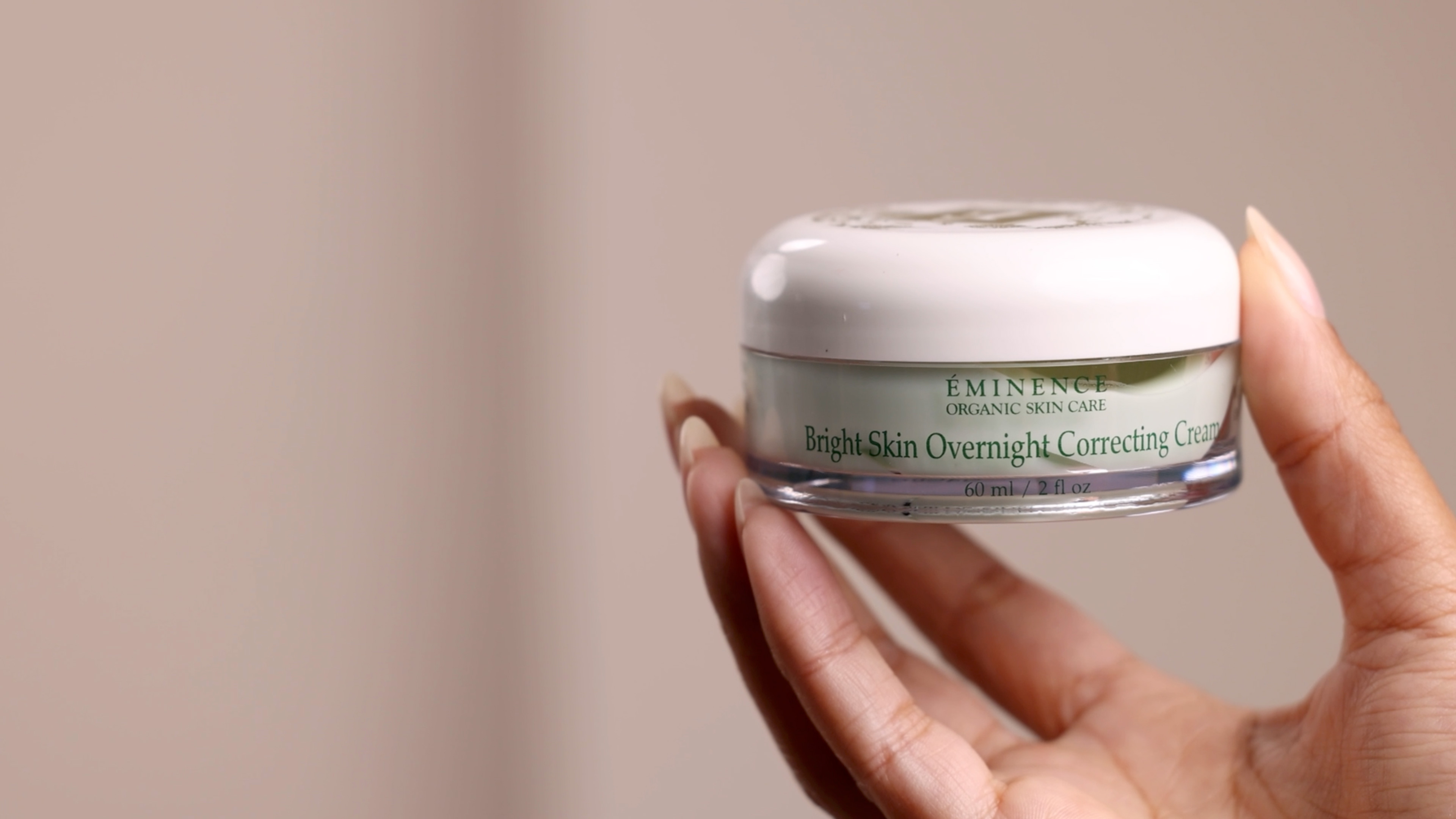 A woman holding Eminence Organics Bright Skin Overnight Correcting Cream