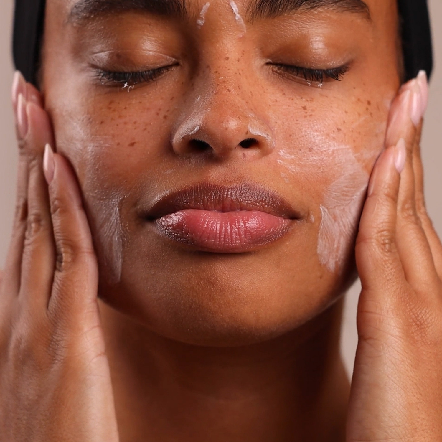 A woman applying the Eminence Organics Kombucha Microbiome Leave-On Masque on her face