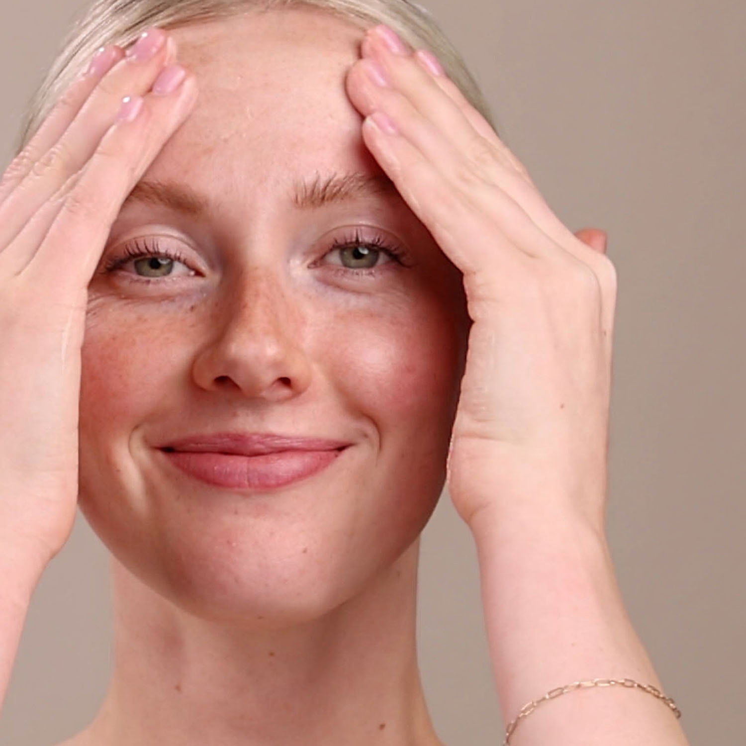 A woman applying the Eminence Organics Linden Calendula Treatment to her face with both hands
