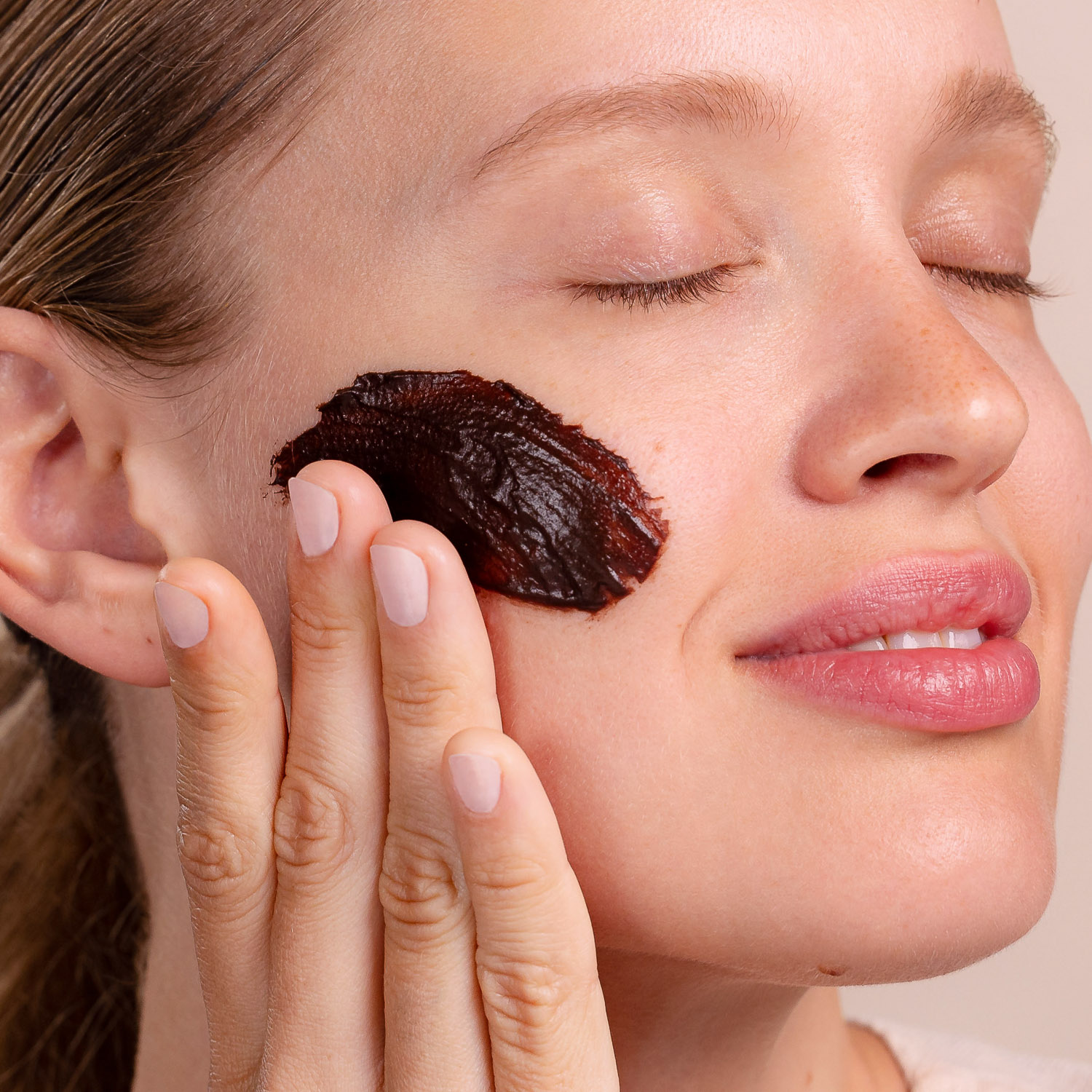 A woman applying Eminence Organics Chocolate Mousse Hydration Masque on face