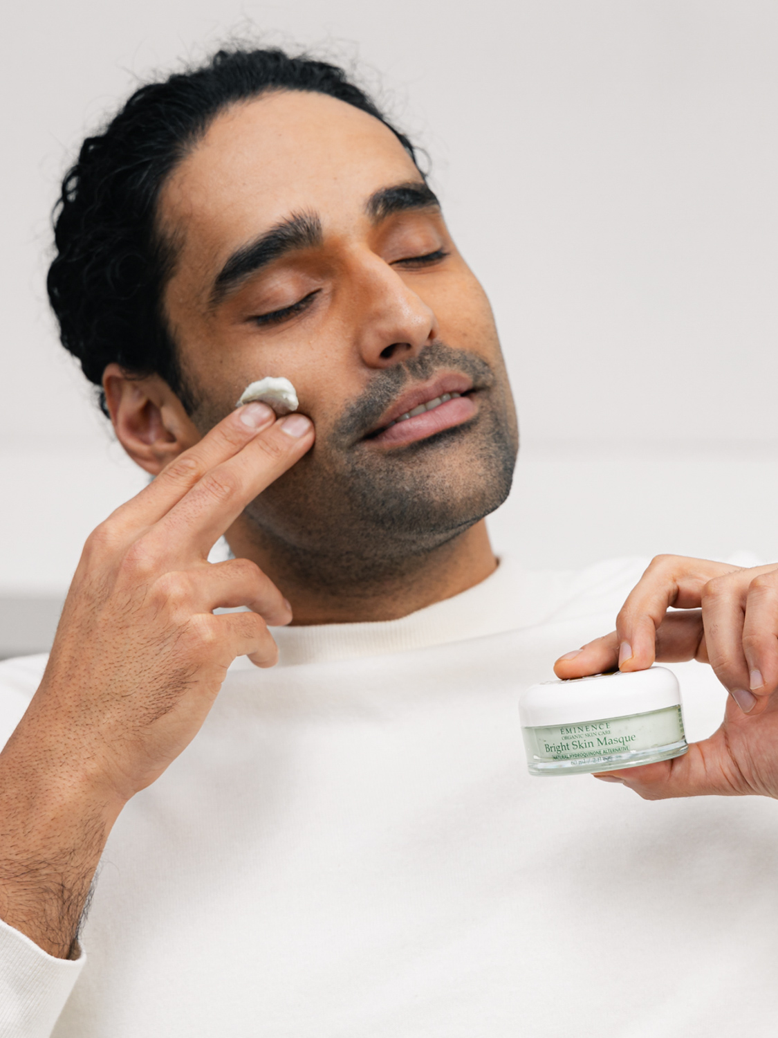 A man applying Eminence Organics Bright Skin Masque to face