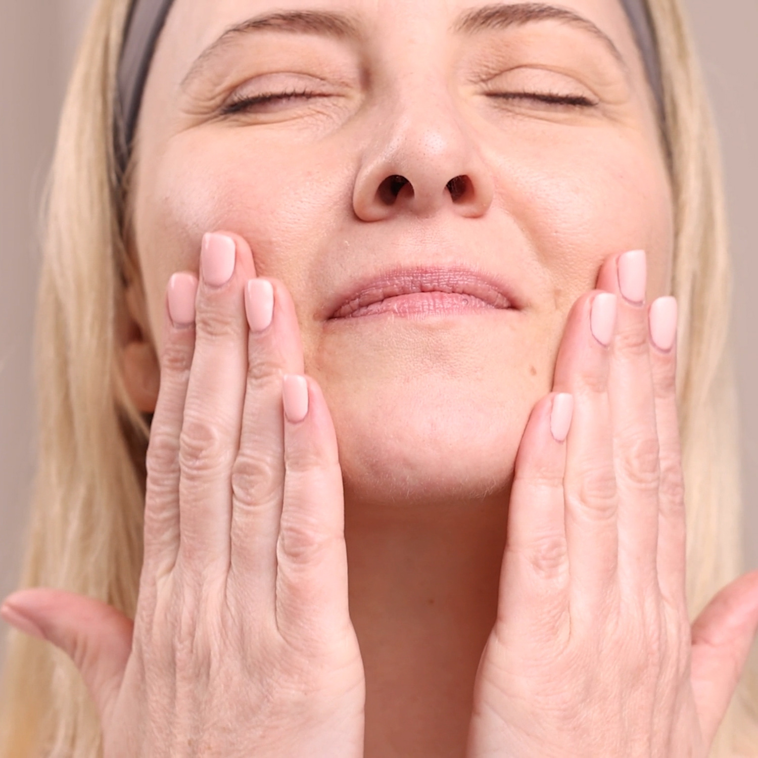 A woman applying the Eminence Organics Marine Flower Peptide Serum to her face