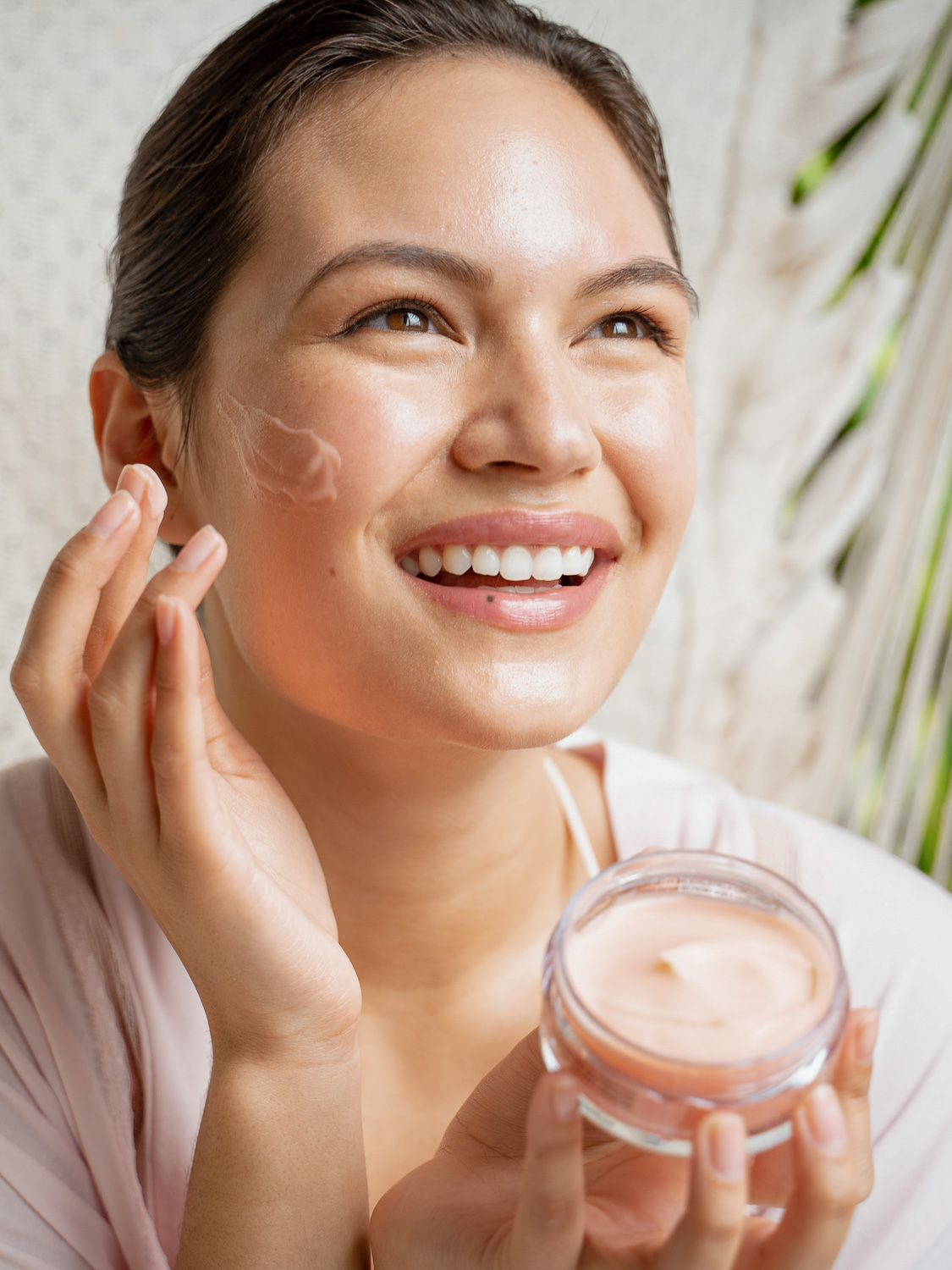 A woman posing with the Eminence Organics Mangosteen Gel Moisturizer in her hand