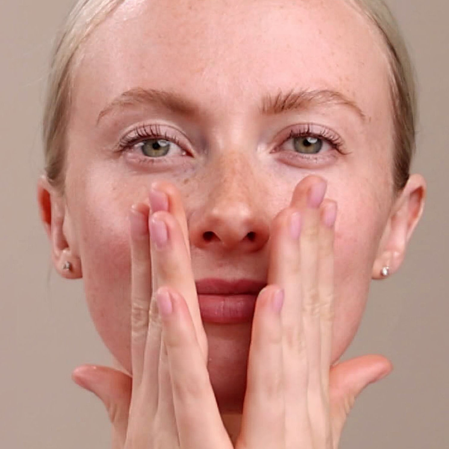 A woman applying the Eminence Organics Marine Flower Peptide Serum to her face