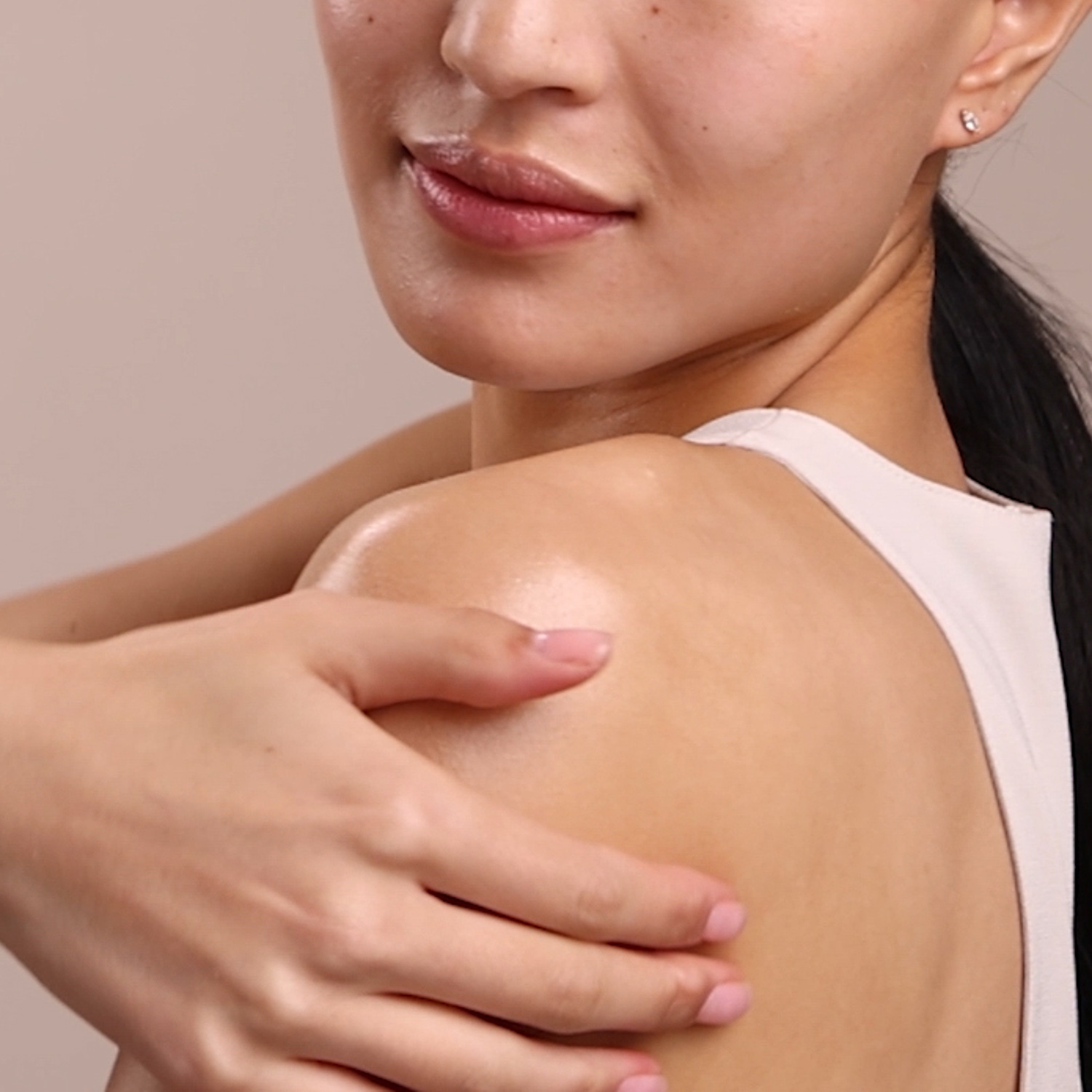 A woman with a swatch of the Eminence Organics Yuzu Solid Body Oil on her shoulder