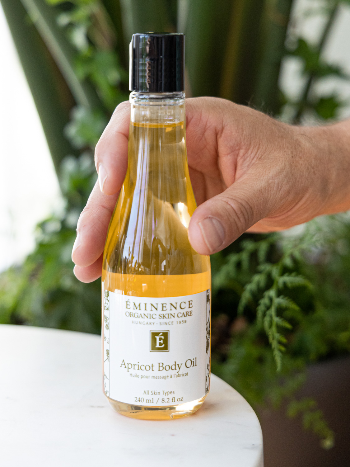 A man's hand holding Eminence Organics Apricot Body Oil