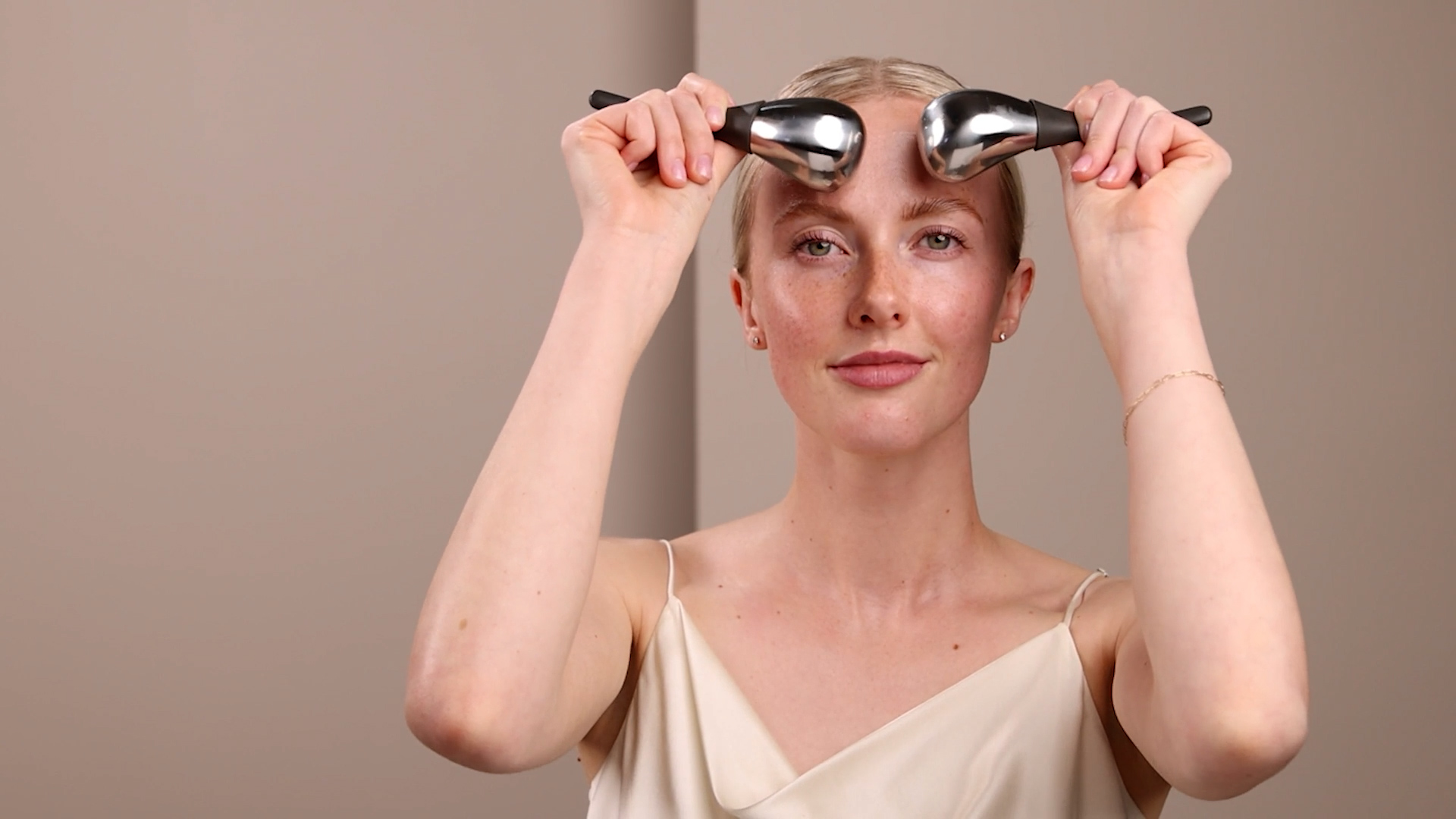 A woman using the Eminence Organics Cryo-Thermal Sculpting Tool on her face