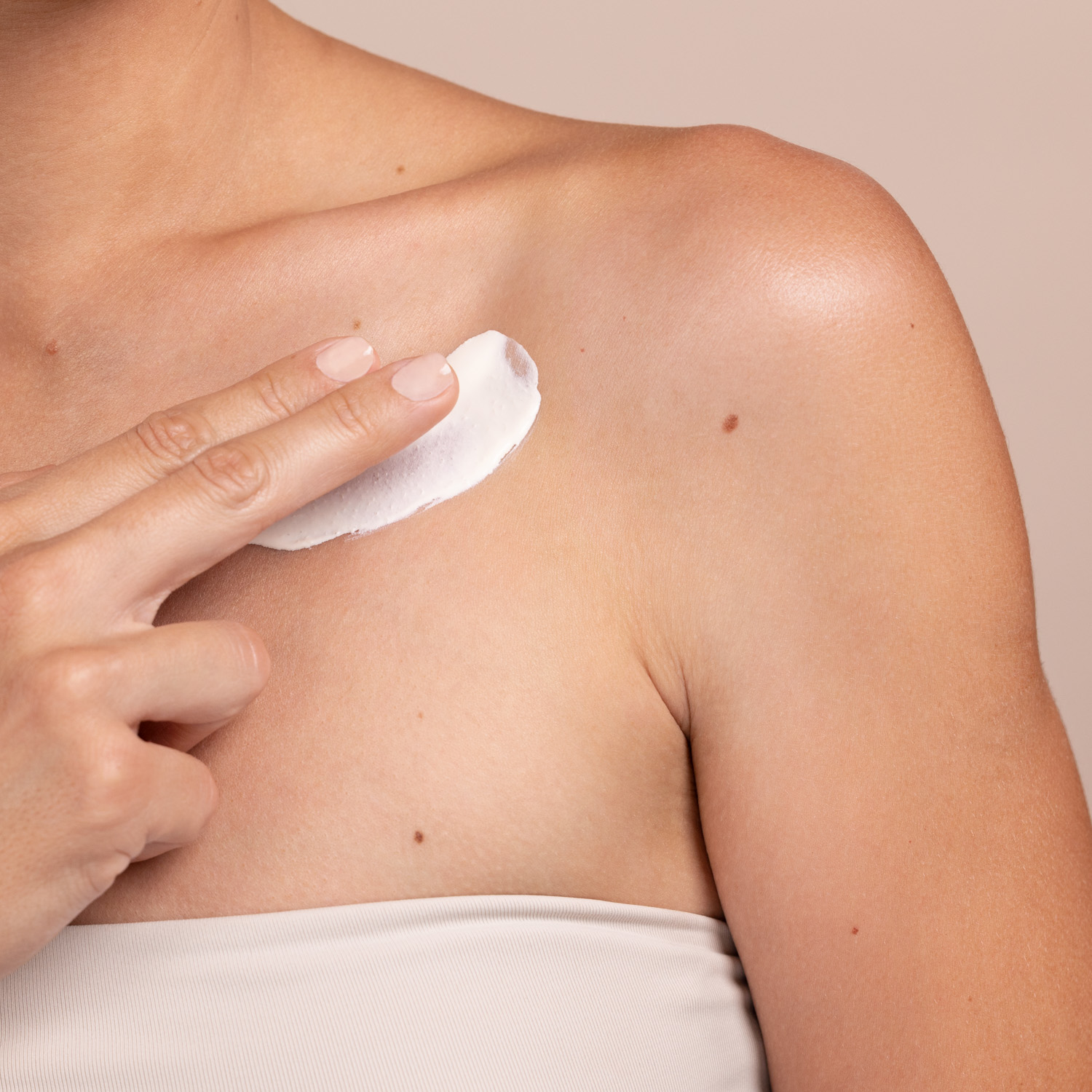 A woman applying the Eminence Organics Lilikoi Mineral Defense Sport Sunscreen SPF 30 on her chest