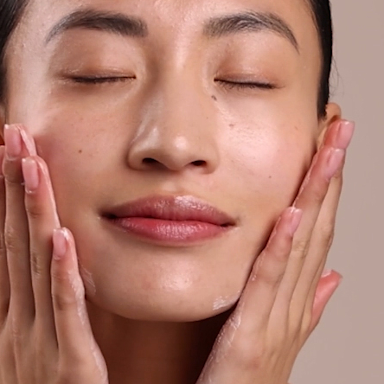 A woman applying Eminence Organics Blueberry Soy Night Recovery Cream to face