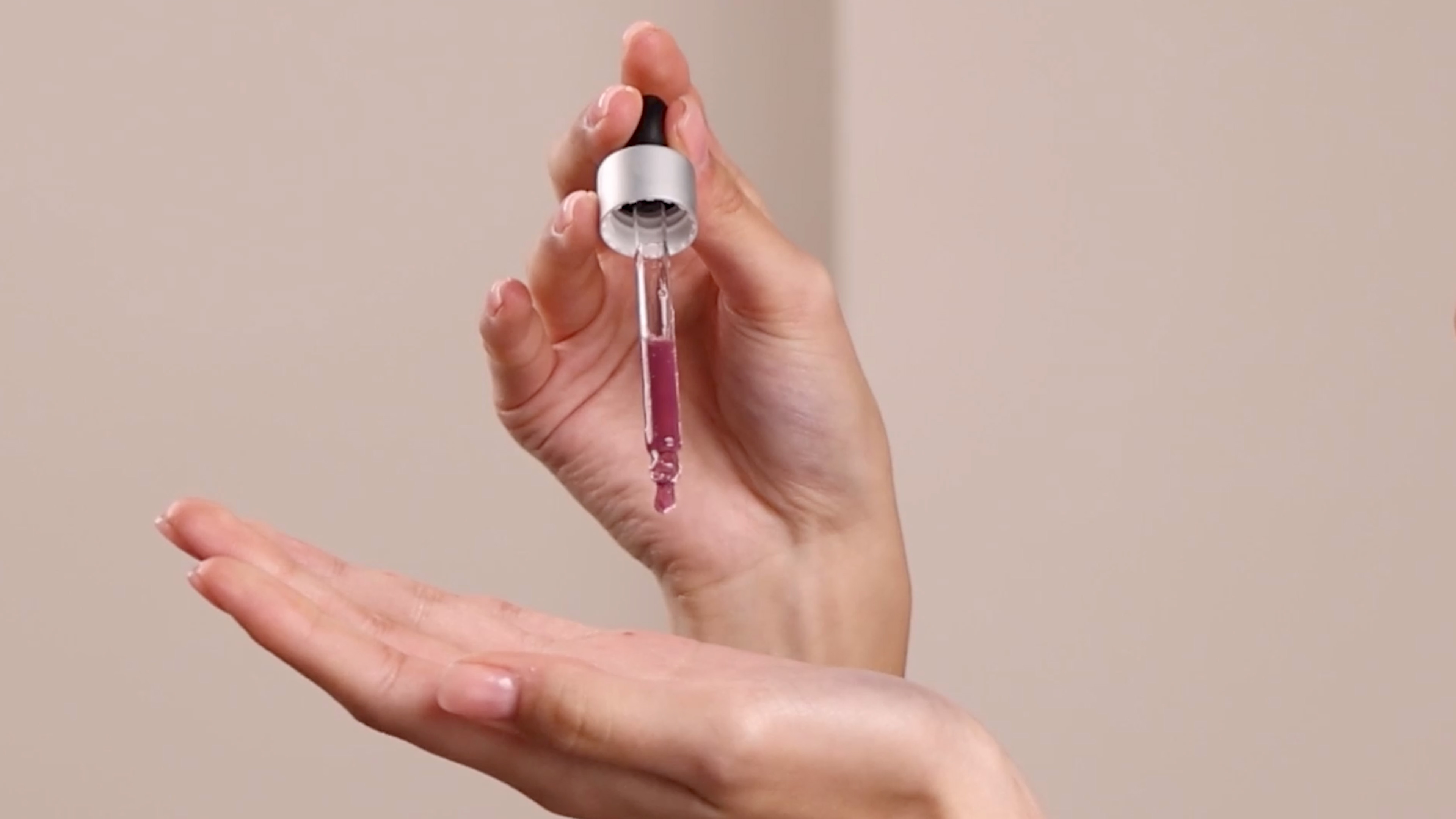 Two hands holding the Eminence Organics Firm Skin Acai Booster-Serum dropper