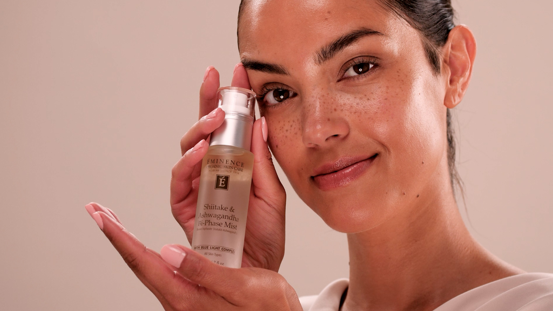A woman holding Eminence Organics Shiitake & Ashwagandha Bi-Phase Mist 