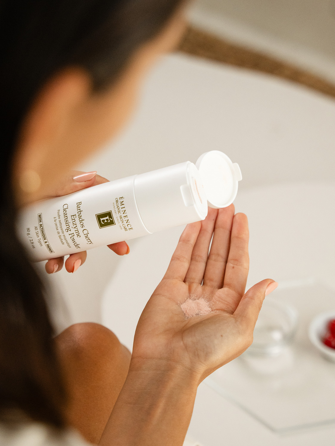 A woman holding Eminence Organics Barbados Cherry Enzyme Cleansing Powder