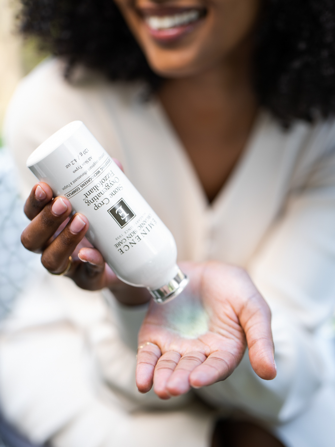 A woman pouring the Eminence Organics Stone Crop Oxygenating Fizzofoliant™ powder on her hand