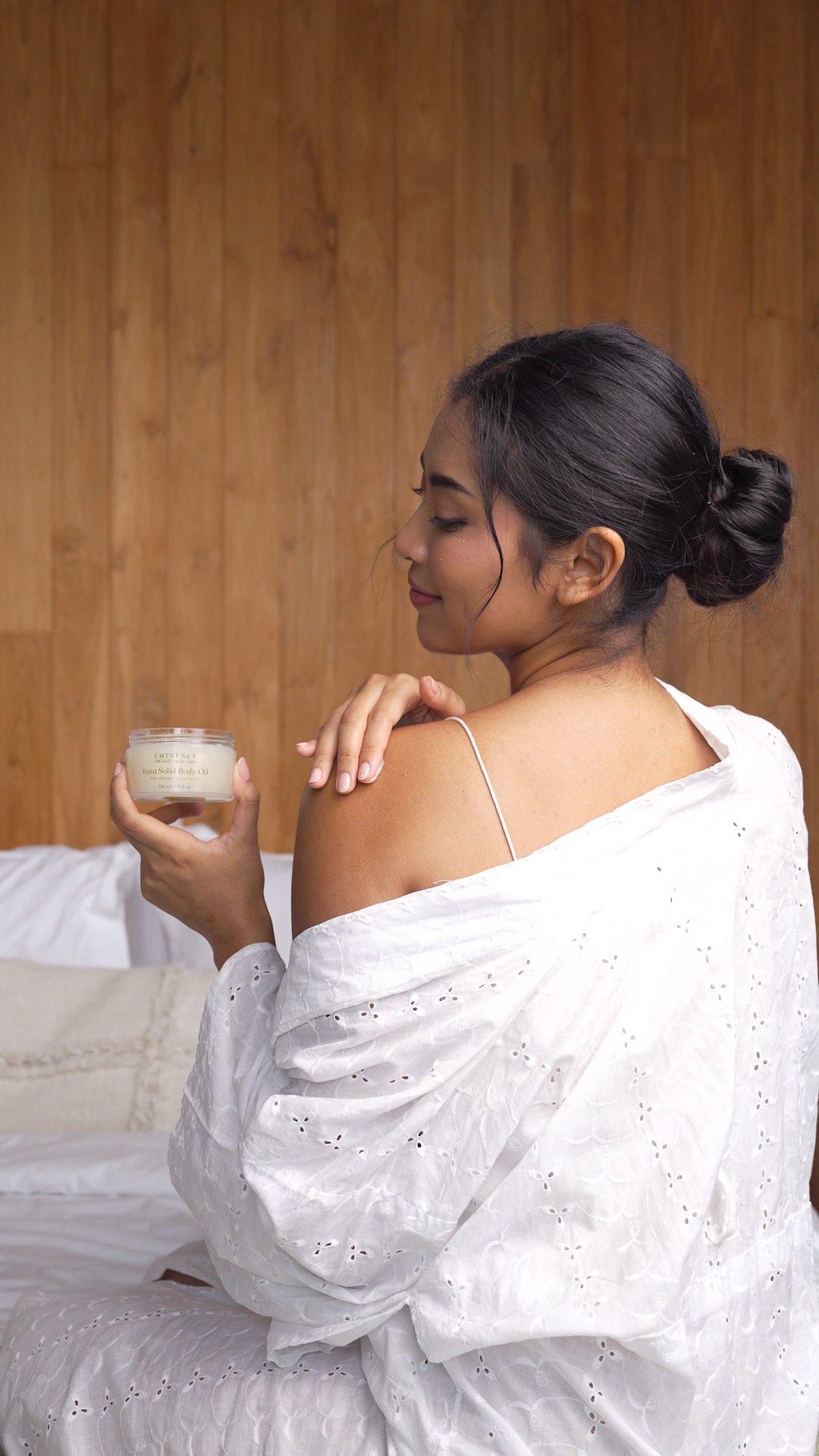 A woman holding the Eminence Organics Yuzu Solid Body Oil