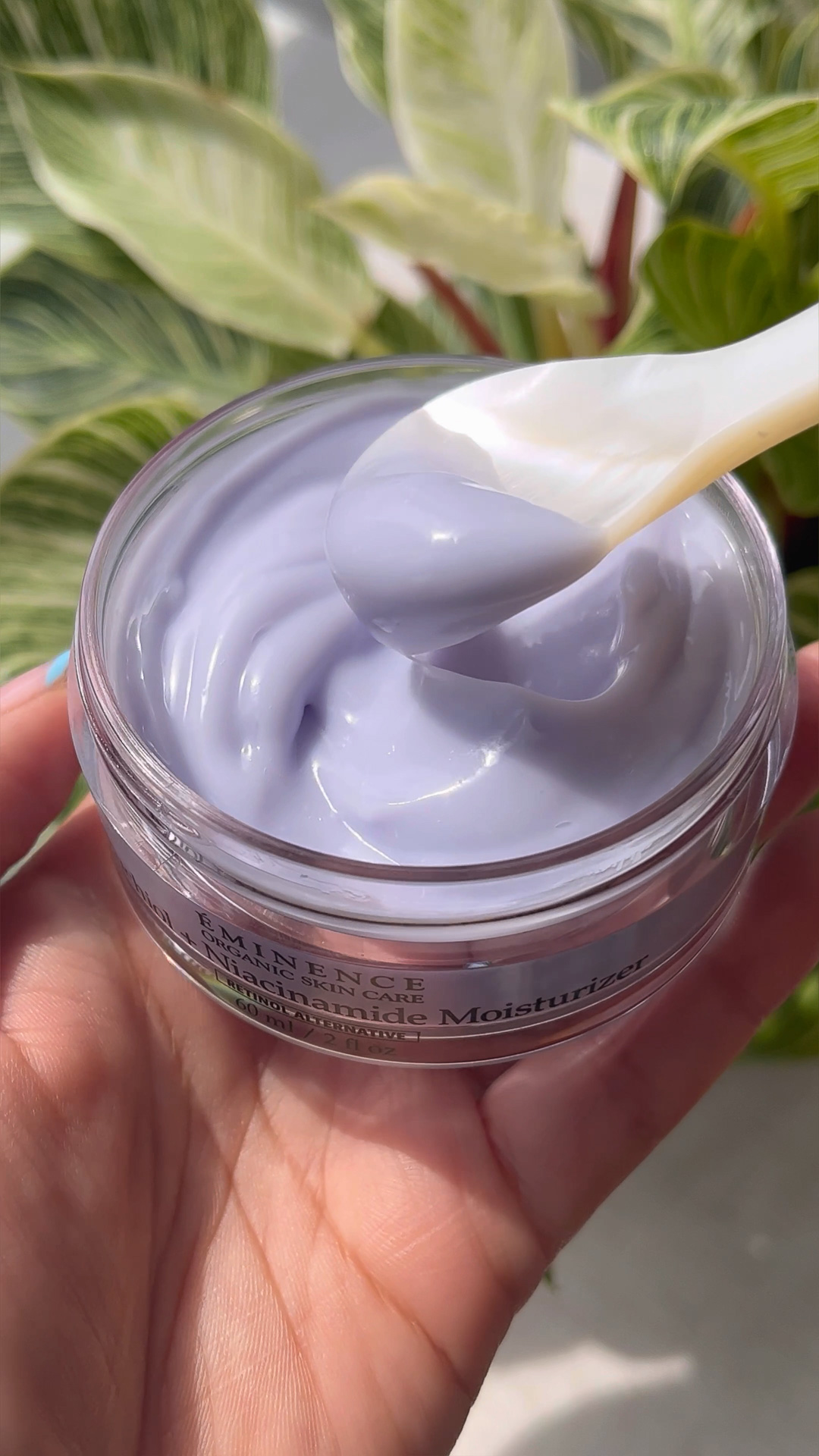 A hand holding Eminence Organics Bakuchiol + Niacinamide Moisturizer 