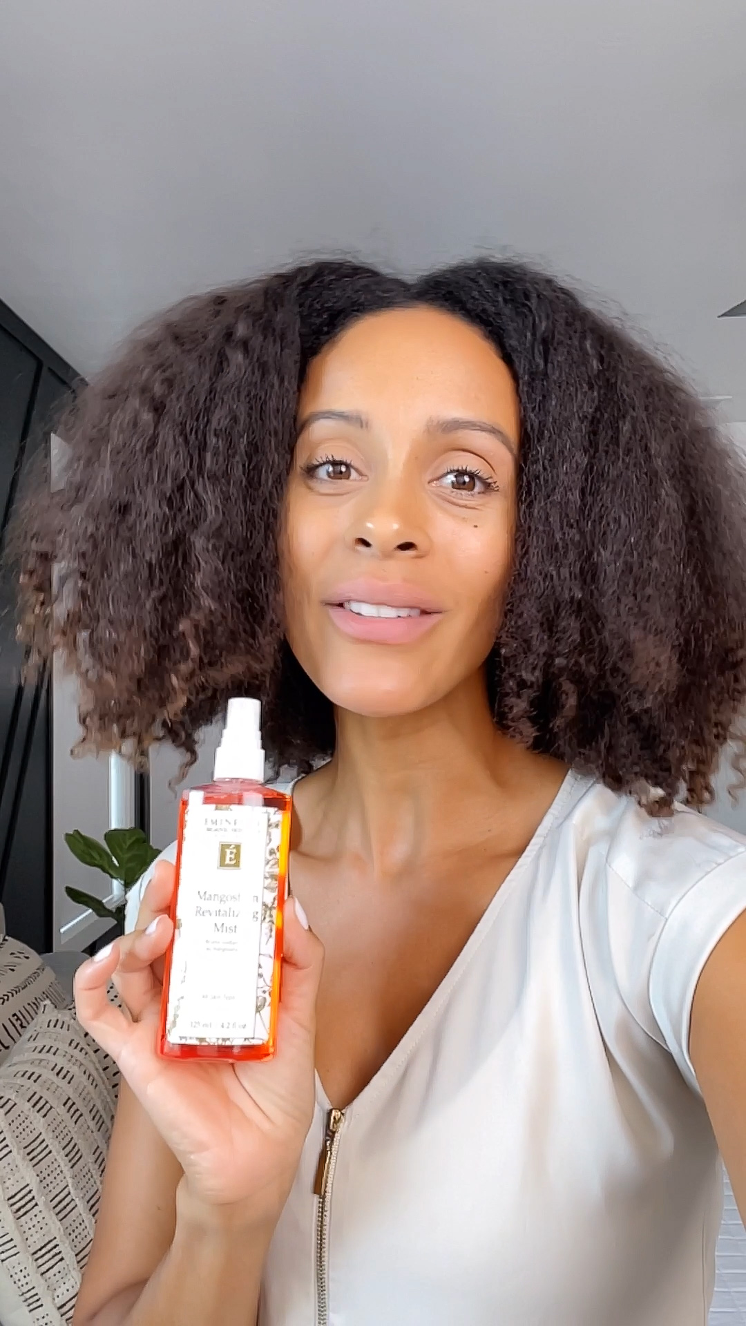 A woman holding the Eminence Organics Mangosteen Revitalizing Mist bottle
