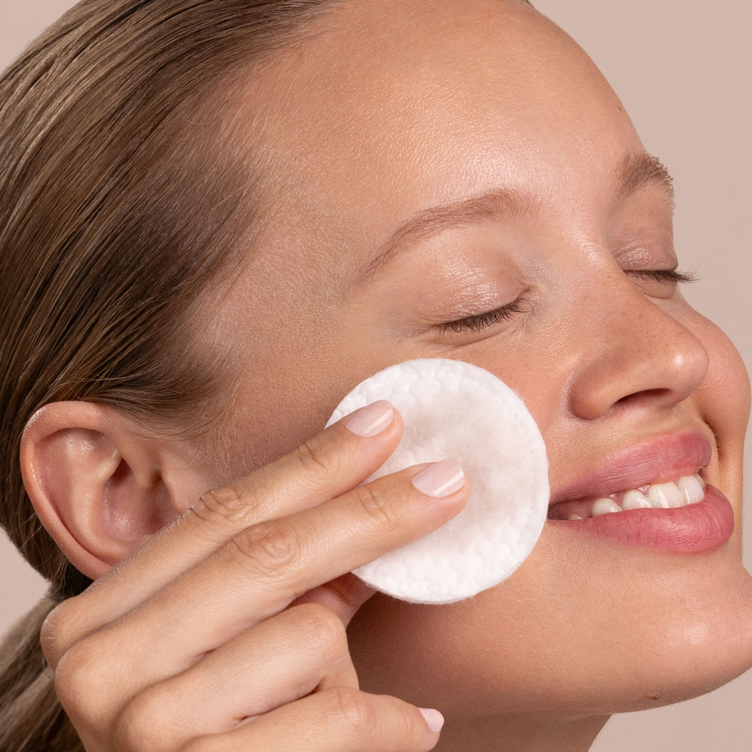 A woman applying Eminence Organics Calm Skin Chamomile Exfoliating Peel to face