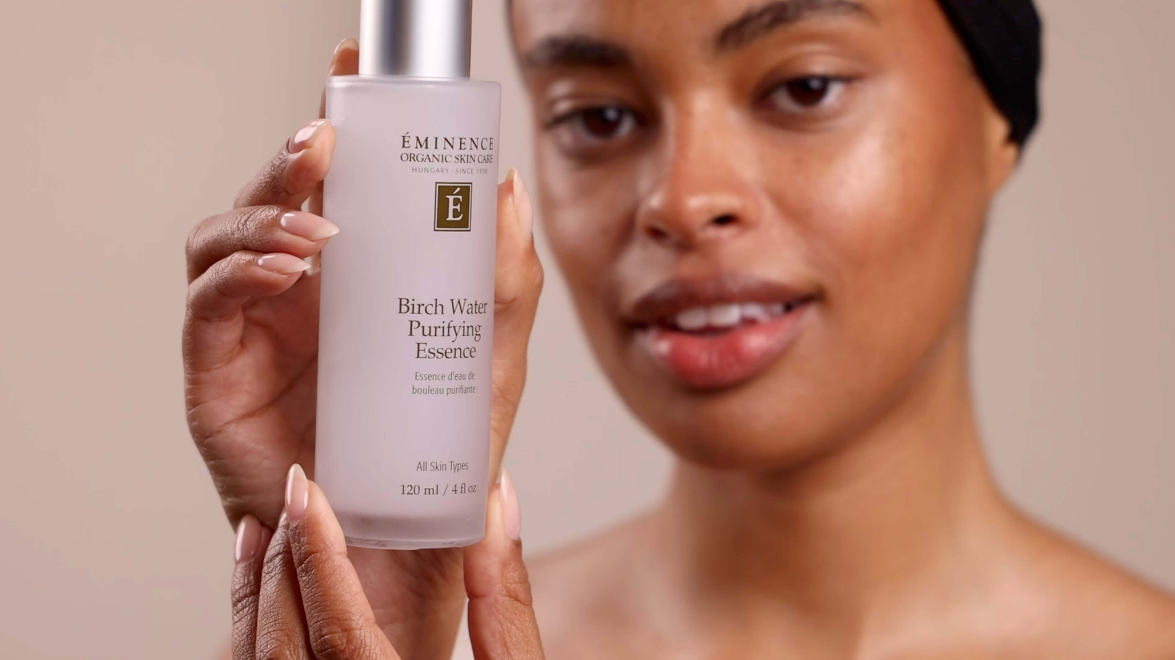 A woman holding Eminence Organics Birch Water Purifying Essence