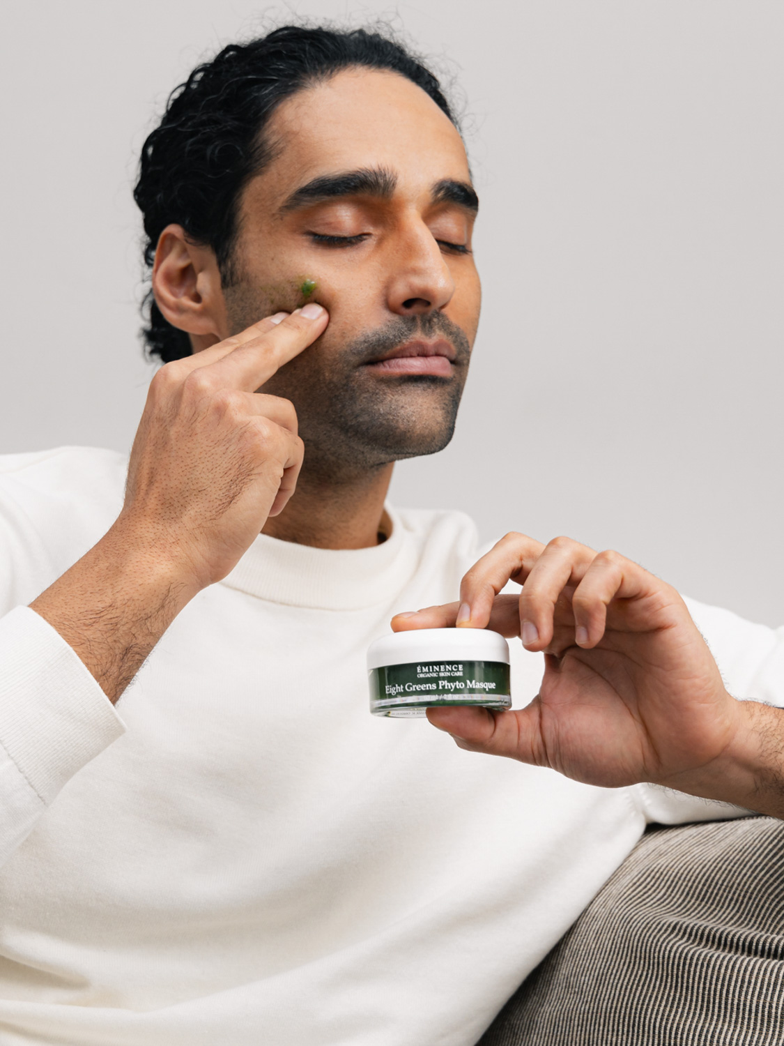 A man applying the Eminence Organics Eight Greens Phyto Masque – Not Hot to his face