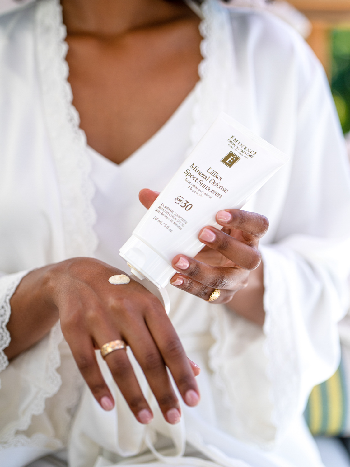 A woman placing the Eminence Organics Lilikoi Mineral Defense Sport Sunscreen SPF 30 into her purse