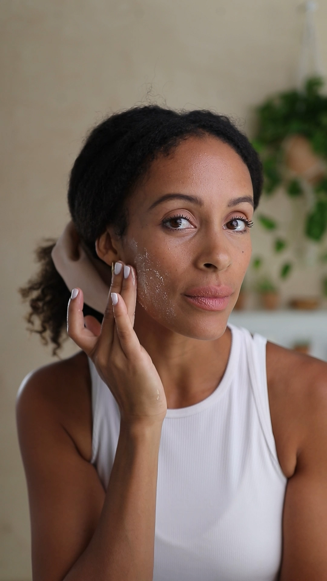 A woman applying the Eminence Organics Strawberry Rhubarb Dermafoliant on her face