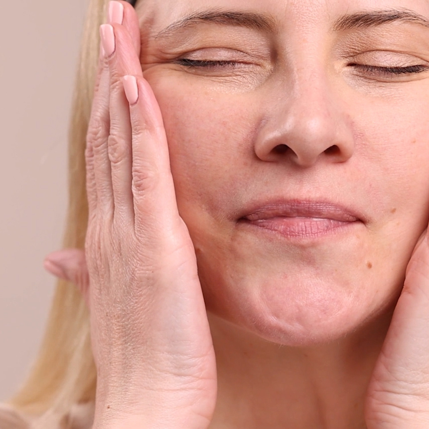 A woman applying Eminence Organics Camellia Glow Solid Face Oil to the face