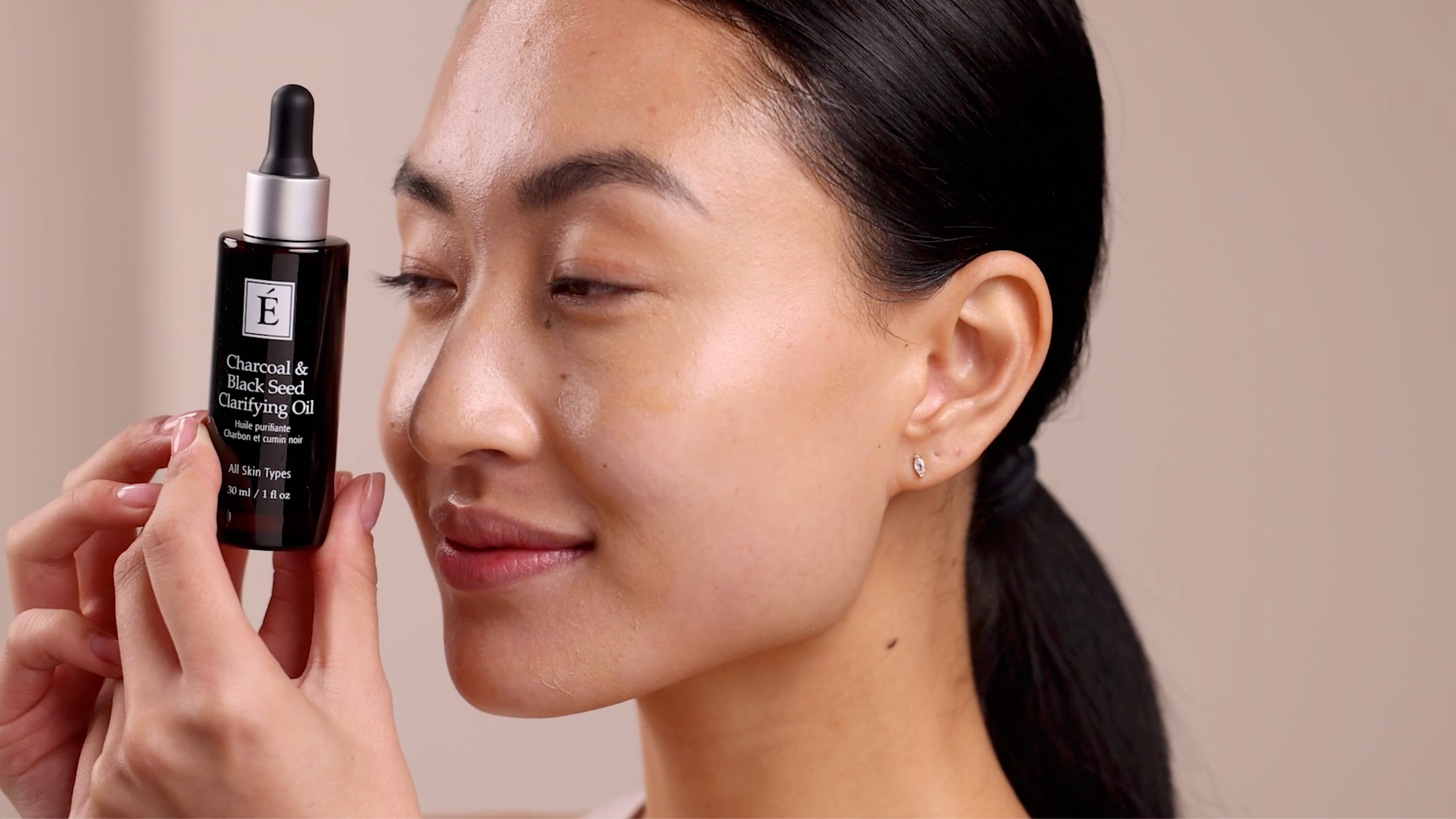 A woman holding Eminence Organics Charcoal & Black Seed Clarifying Oil