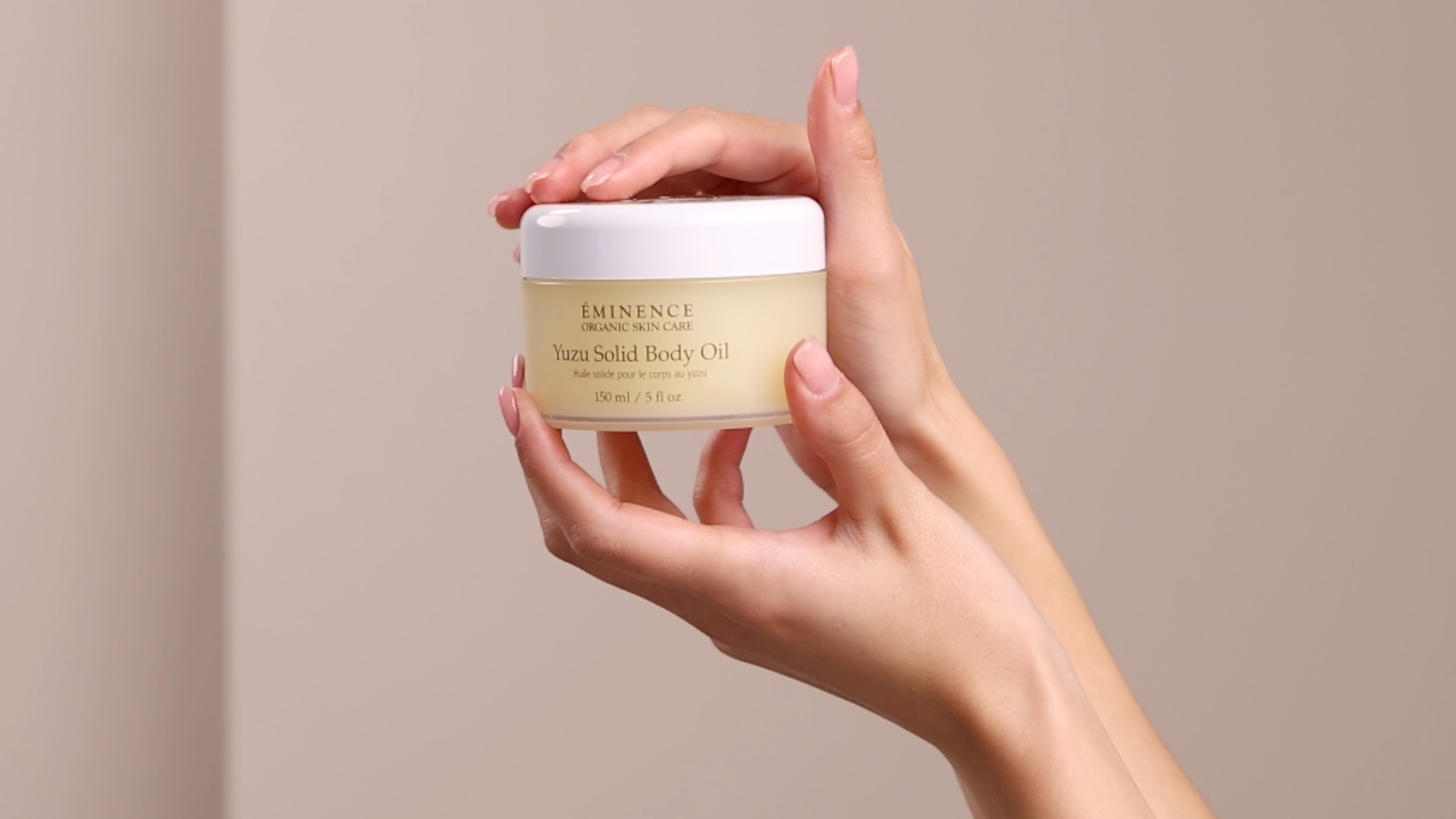 Hands holding the Eminence Organics Yuzu Solid Body Oil