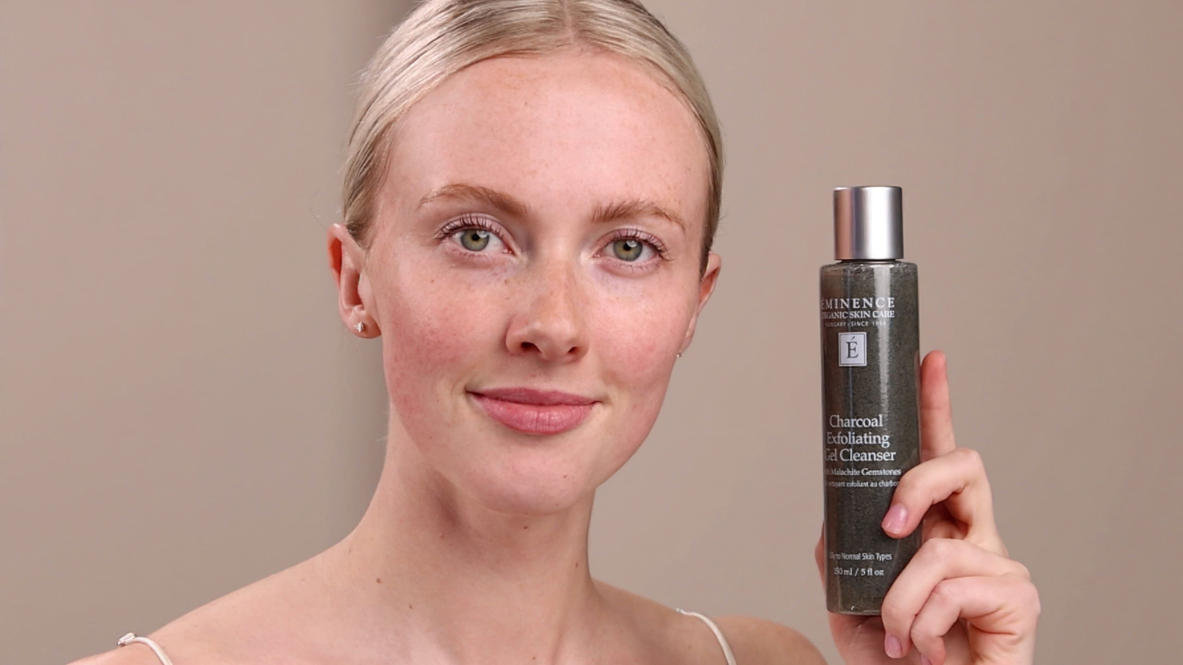 A woman applying Eminence Organics Charcoal Exfoliating Gel Cleanser to hand