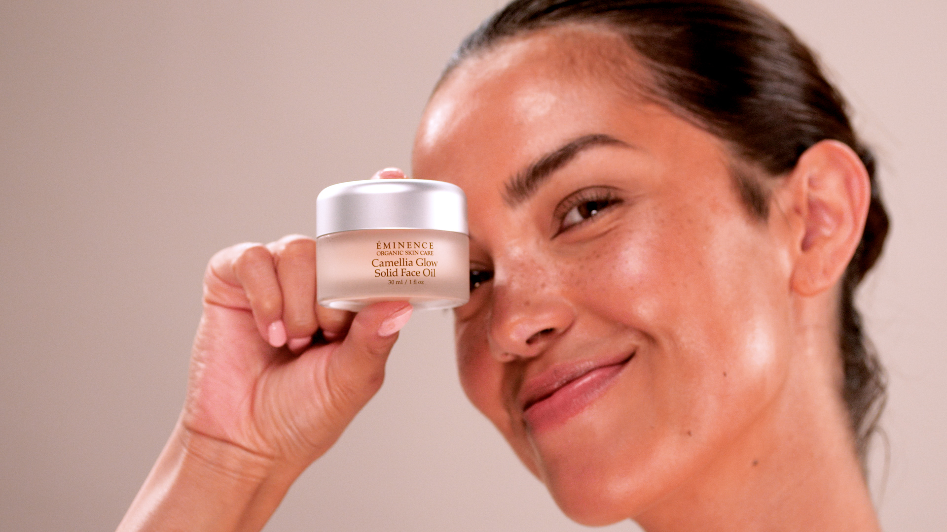 A woman holding Eminence Organics Camellia Glow Solid Face Oil