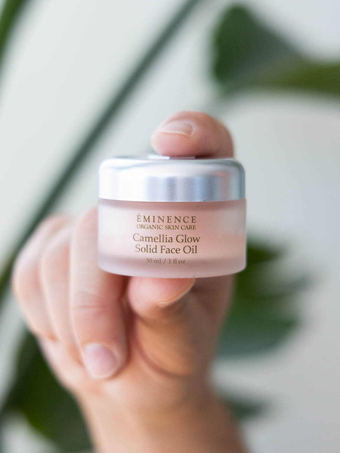 A person holding Eminence Organics Camellia Glow Solid Face Oil