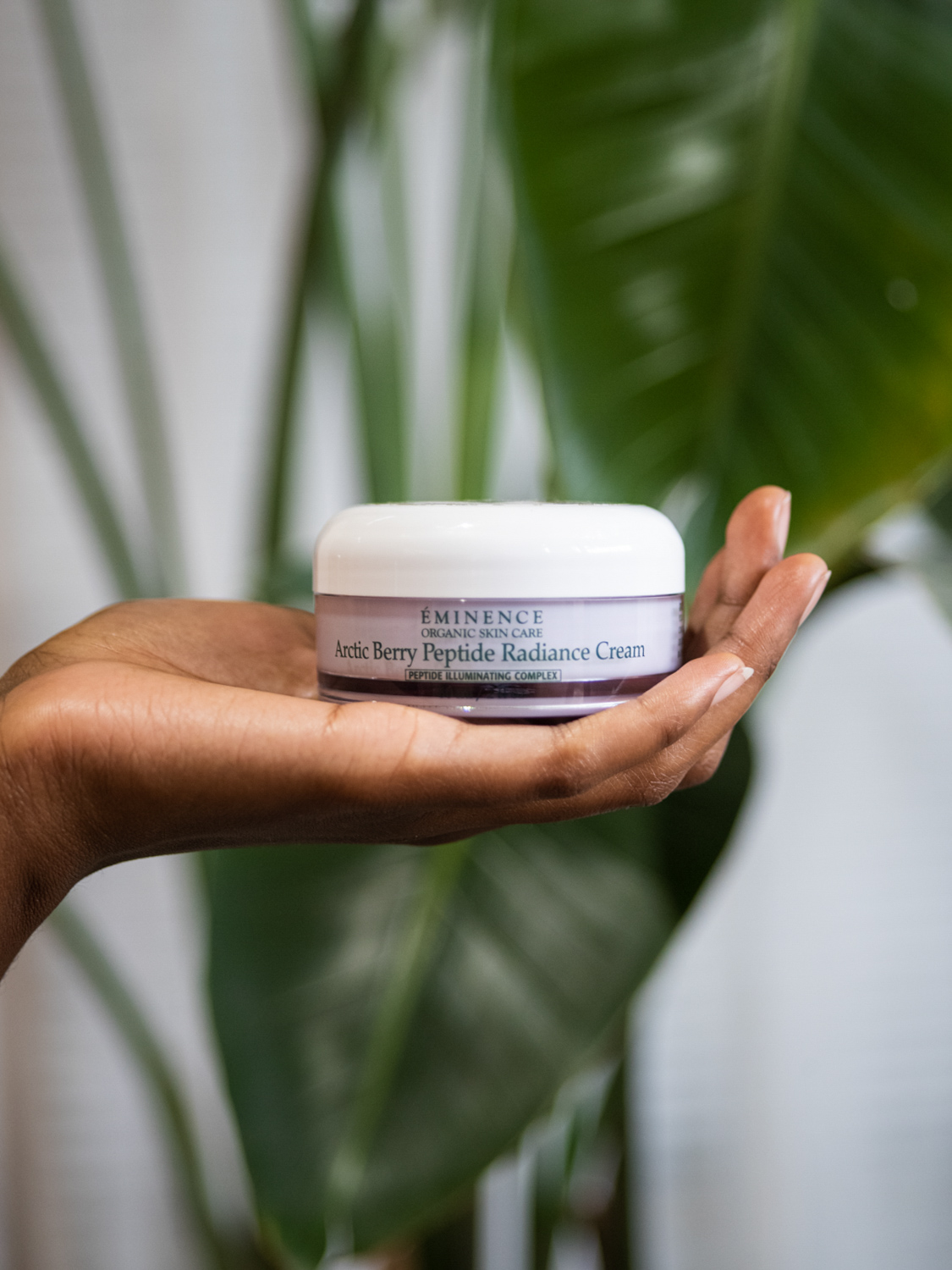 A hand holding Eminence Organics Arctic Berry Radiance Cream