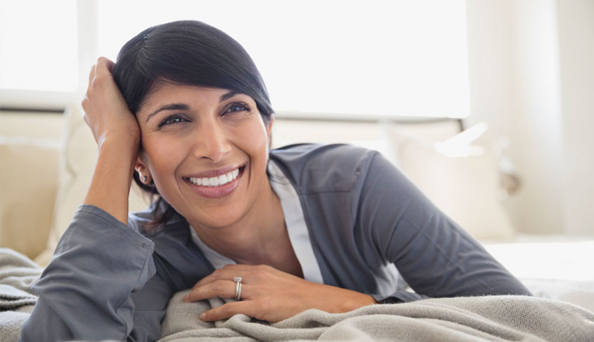 Closeup smiling woman on bed in bedroom