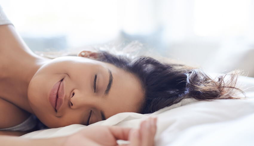 Woman laying on a pillow smiling with eyes closed