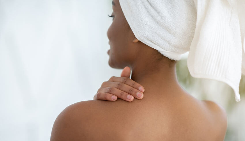 Woman with towel on head touching her bare back