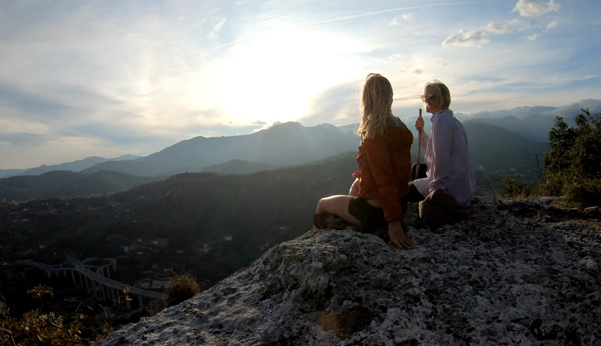 2 women watching the sunset from a mountain top. 