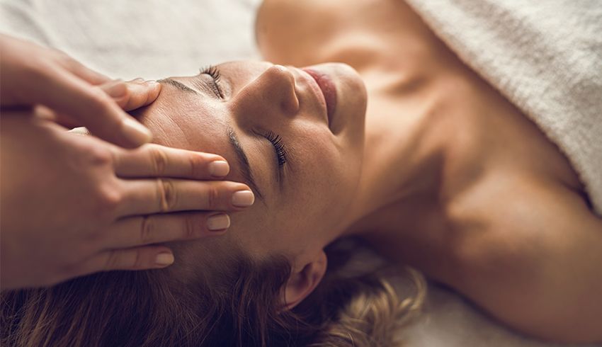A woman at a spa receiving a facial massage 