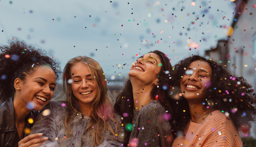 Four women laughing with confetti