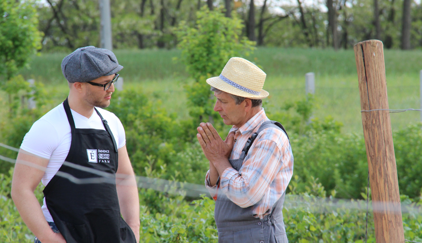 Eminence Organics President Boldijarre Koronczay and an organic farmer stop to talk in a field.