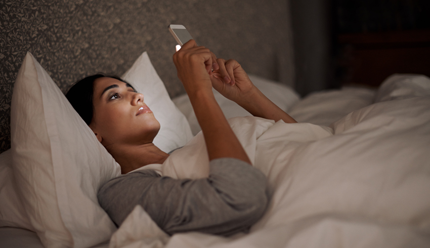 Woman looking at cell phone in bed