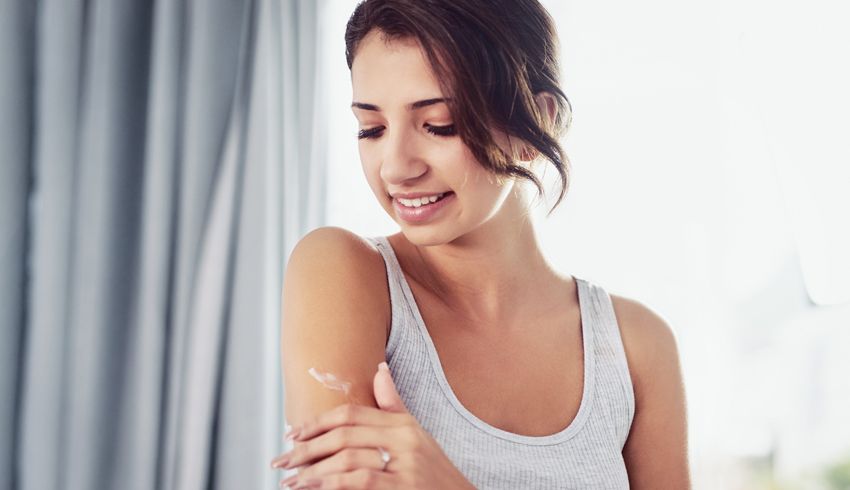Young woman moisturizing arm