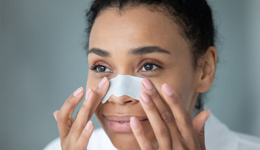 Woman looking in mirror with pore strip over nose