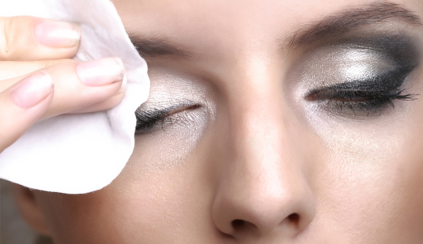 Woman wiping away eye makeup with a makeup wipe.