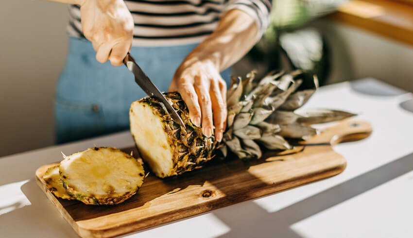 A woman cutting a pineapple