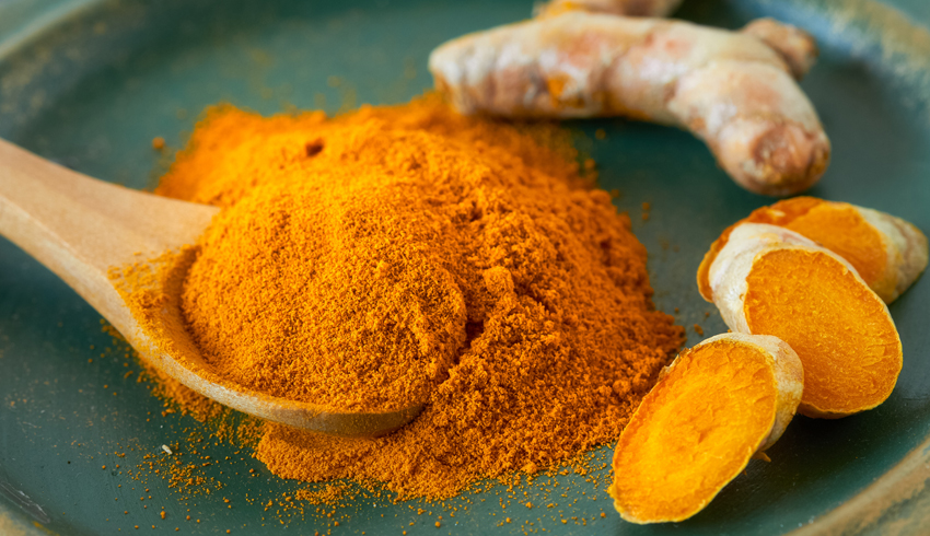 Powdered and root turmeric spice on a plate