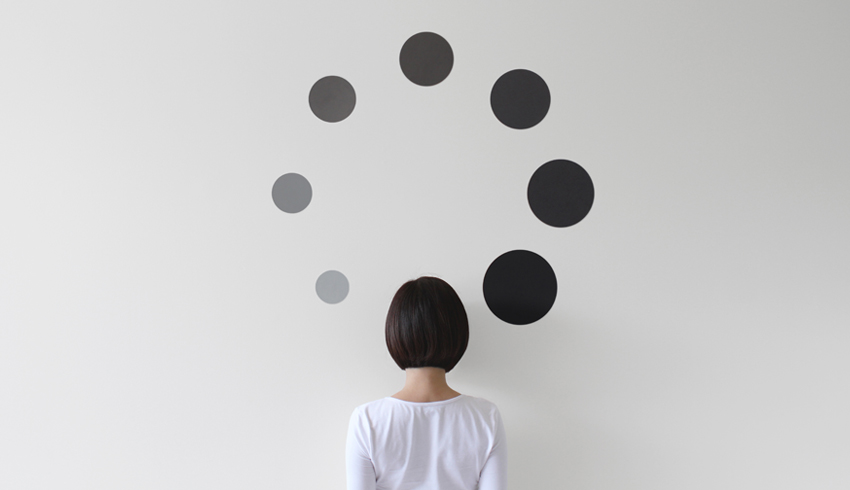 Woman facing wall surrounded by black spots